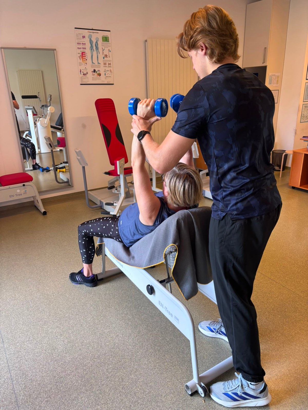 Jan betreut eine Patientin beim Hanteltraining im Trainingsraum